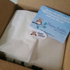 Cardboard box with tissue paper covering the contents. Sticker with text &quot;Diaper Dabbler diaper variety pack&quot; sealing the sheets of tissue paper. Blue card on top with text &quot;we hope this variety pack of diapers helps you find the perfect fit for your litt